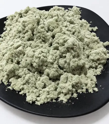 Light green-grey milled cellulose fibre heaped on a black plate