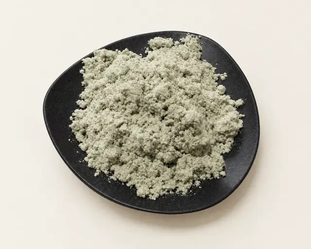 Grey milled cellulose fibre heaped on a black plate, on off-white paper