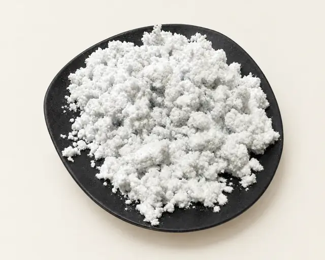 White milled cellulose fibre heaped on a black plate, on off-white paper